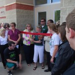 Board President, Janet Grey (left) and Superintendent Dr. Oliver Robinson (right) stand beside Girls Swim Coach, Pat Seligman as she performs the ribbon cutting